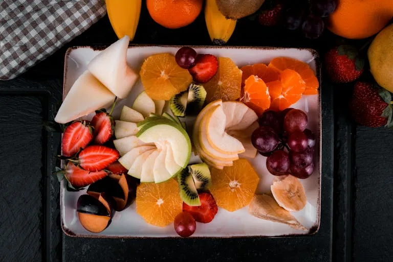 Colorful assortment of sliced fresh fruits on a decorative plate, perfect for healthy snacking.